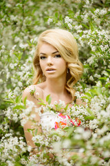 Young spring fashion woman. Trendy girl in the flowering trees i