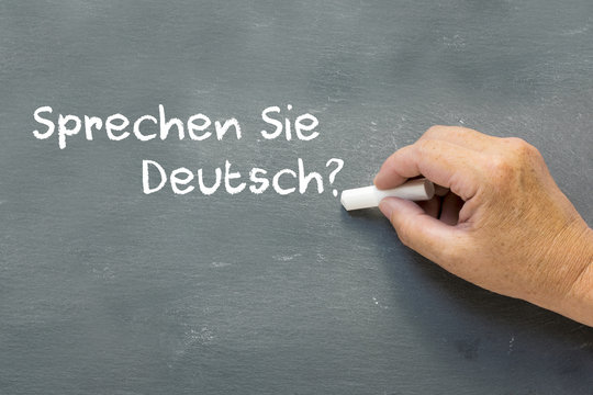 Hand on a chalkboard with the German words Sprechen Sie deutsch