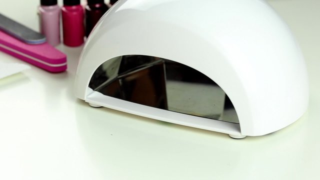 Manicure in process - putting hand and curing gel varnish in nail LED lamp, procedure of polymerization