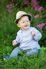 Toddler sitting on the grass in a meadow. A baby on the background