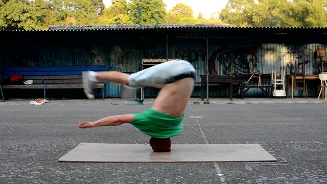 Crazy boy spins on his head on the street