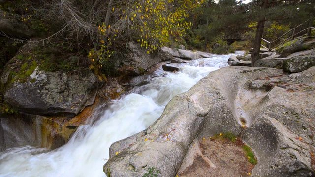 Water flowing under an ancient wood bridge in river Eresma at Boca del Asno natural park on a rainy day in Segovia, Spain. 