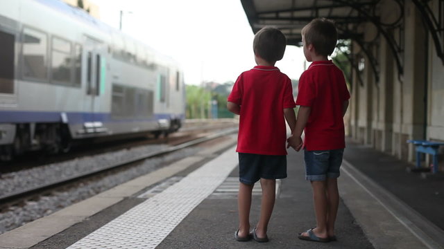 Two boys, watching a train leaving a station