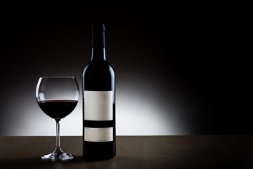Bottiglia di vino rosso con bicchiere su sfondo nero