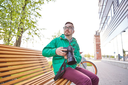 young hipster man with digital camera in city
