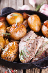 Roasted young potatoes in the pan. With meat, garlic , bacon and thyme.selective focus