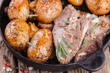 Roasted young potatoes in the pan. With meat, garlic , bacon and thyme.selective focus