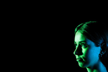 Beautiful young woman's face in blue and green lights at the cor