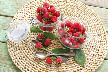 Glass cup and jar  with raspberries on table