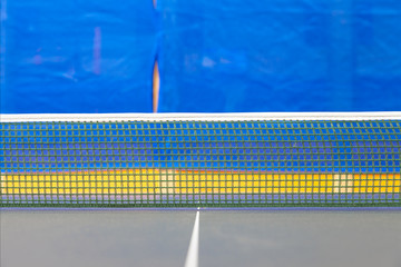Table tennis net in focus with yellow and blue background