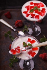 Yogurt with strawberry jelly in a glass glass, on a dark background.