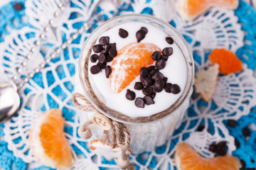 The homemade yogurt in a jar with tangerines and chocolate