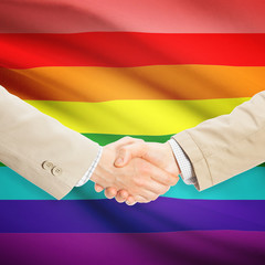 Businessmen handshake with flag on background - LGBT people