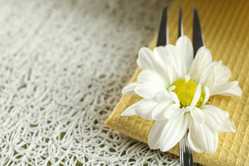 Fork with beautiful flower on table close up