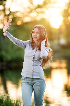 Romantic young girl holding a smartphone digital camera with her