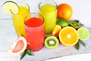Glasses of different juice with fruits and mint on table close up