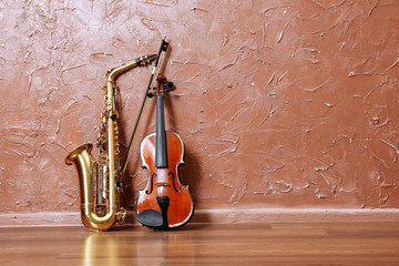 Saxophone and violin on brown wall background