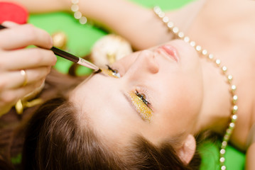 Closeup of applying makeup on face of lying brunette girl