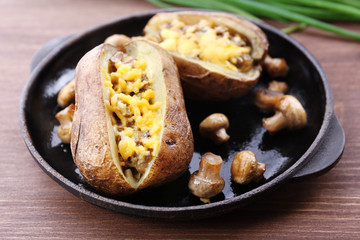 Baked potatoes with cheese and mushrooms on table close up