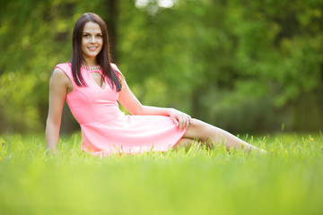 Young spring fashion woman sitting on the grass. Trendy girl in