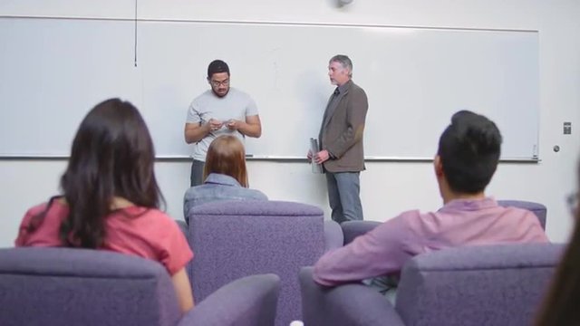 A very nervous student gives a speech in front of his class
