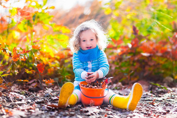 Little girl picking acorns in autumn park © famveldman