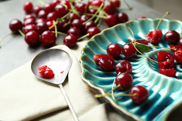 Sweet cherries on plate, on dark background