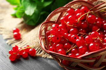 Ripe red currant in wicker basket on wooden background