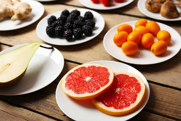 Different products on saucers on wooden table close up