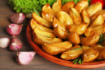 Baked potato wedges on wooden table, closeup