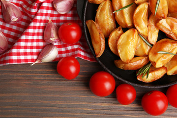 Baked potato wedges on wooden table, closeup