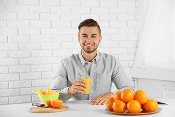 Young man having a table full of fresh oranges and juice