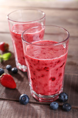 Glasses of berry smoothie on wooden table, closeup