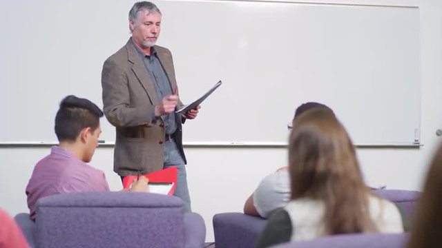 A professor talks to students in the front of his class