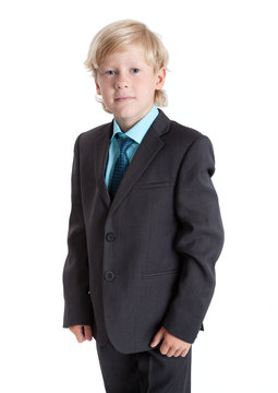Seven years old blond schoolboy in school uniform, suit, shirt and tie, isolated on white background