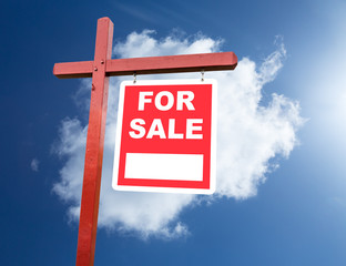 For Sale sign for home in front of blue sky