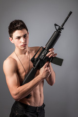 Handsome bare-chested soldier is holding a rifle