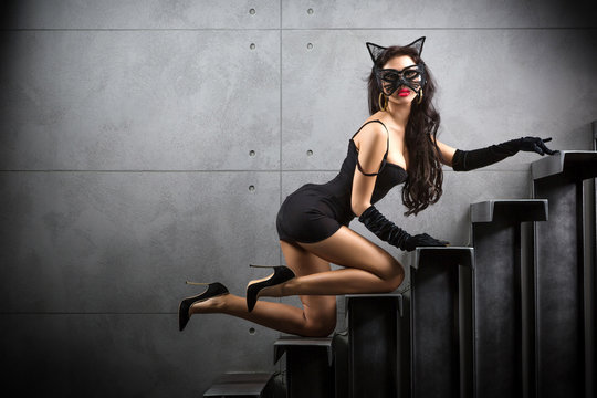 sexy woman in catwoman suit lying on stairs