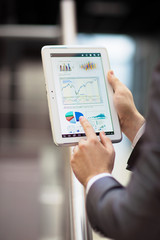 Fototapeta na wymiar Business person analyzing financial statistics displayed on the tablet screen