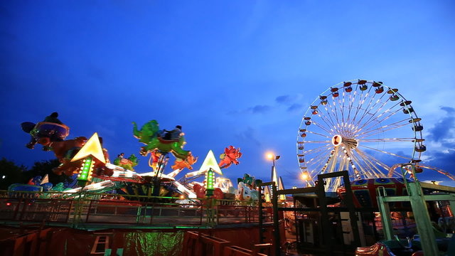 Amusement park at twilight time with ferris wheel in motion