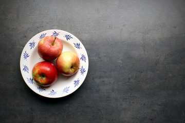 Fresh apples on plate with copyspace on grey kitchen table