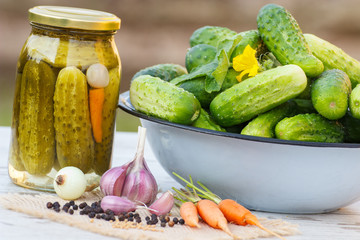 Cucumbers in metal bowl, vegetables and spices for pickling and jar pickled cucumbers