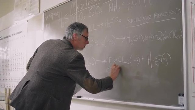 A professor writes formulas on the chalkboard
