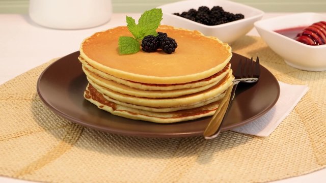 Delicious golden pancakes with fresh blackberries and raspberry jam.