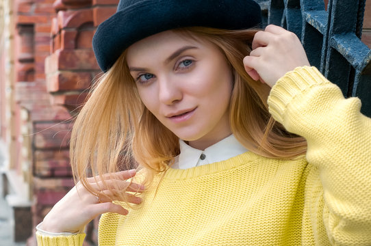 Young Blond Woman In Black Hat And Yellow Sweater