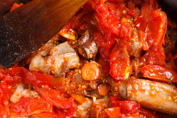 Roasted pork ribs with tomato, carrots and onions on a  frying pan