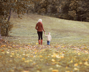 Fototapeta premium Mother and child walking together in autumn park, life moment