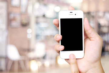 Hand holding smart phone over blur restaurant background