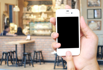 Hand holding smart phone over blur restaurant background