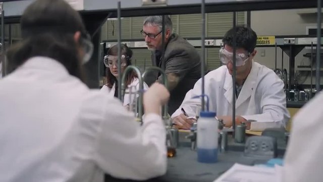 A professor helps his students with their science experiments
